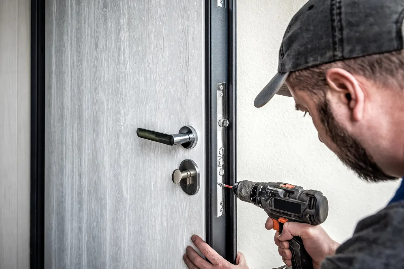 Serrurier du réseau posant un cylindre de sûreté sur une porte d'entrée
